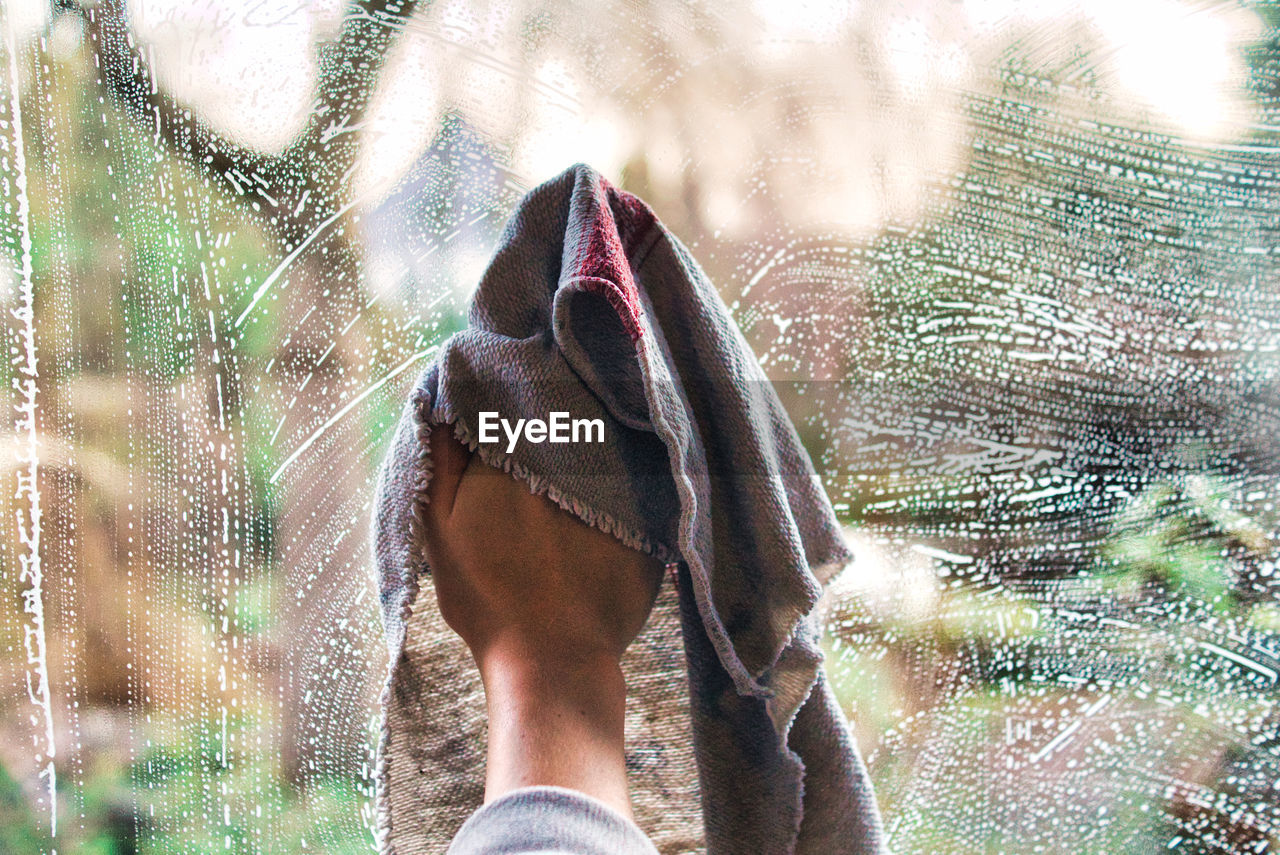 Low section of person cleaning a wet window glass