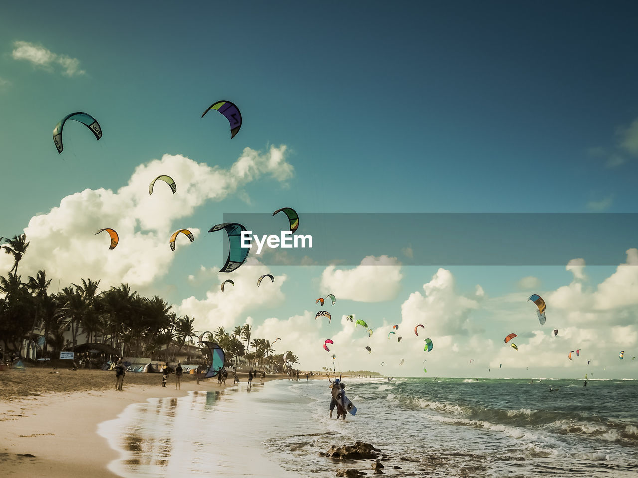 People kiteboarding at beach against sky