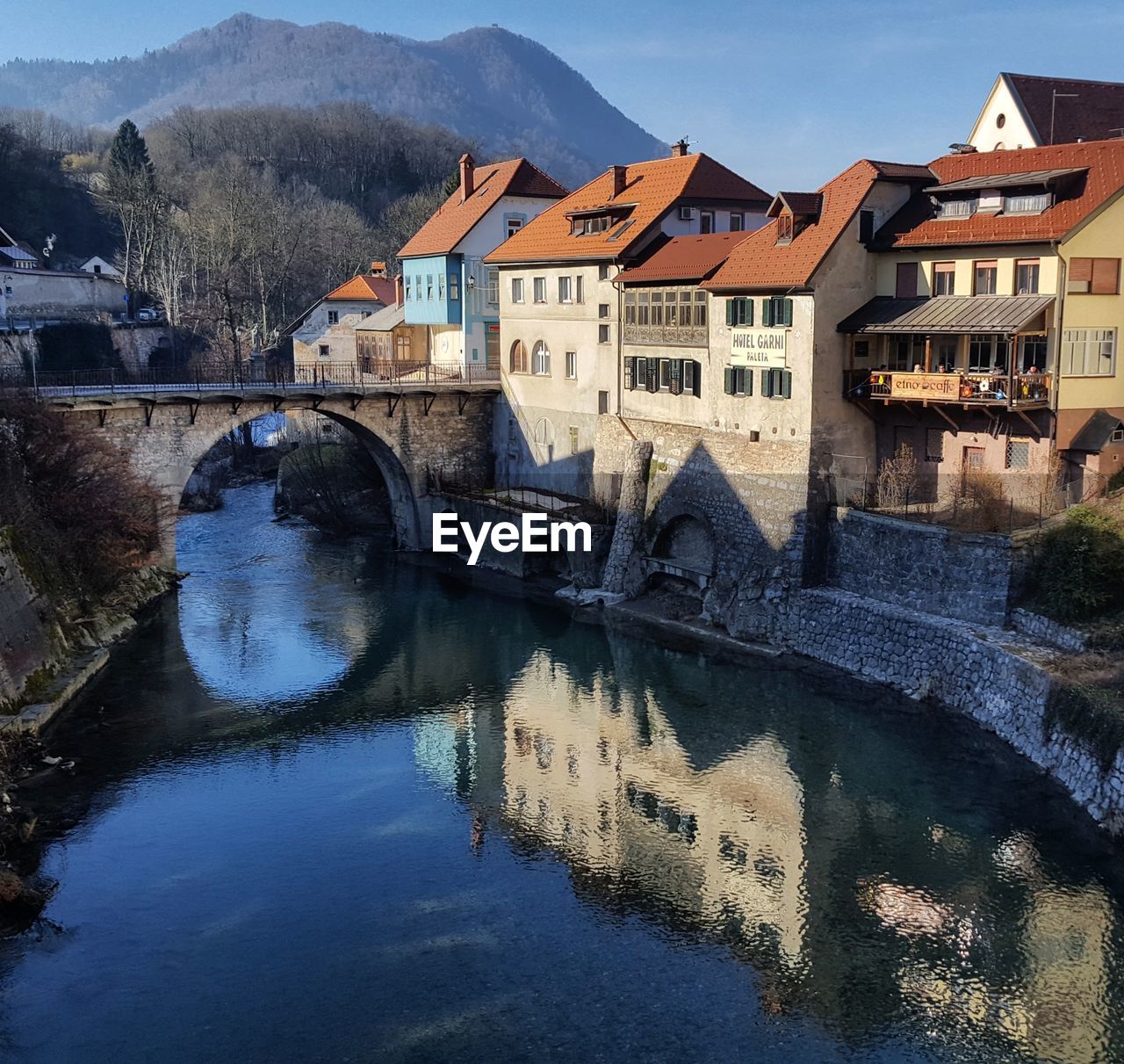 Bridge over river by houses against sky