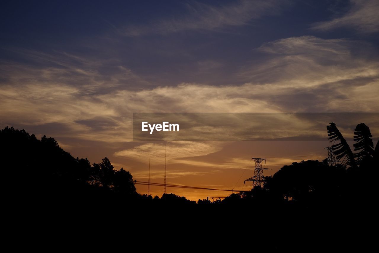 Silhouette trees against cloudy sky during sunset