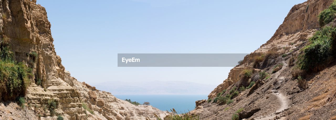 Scenic view of sea and mountains against clear sky