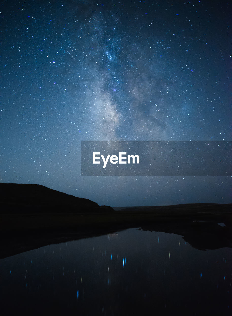 Scenic view of lake against sky at night