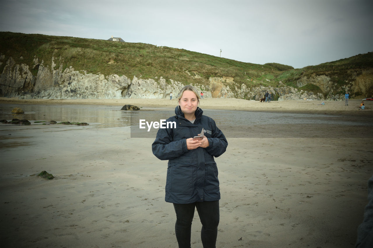 PORTRAIT OF MAN STANDING ON BEACH AGAINST SKY