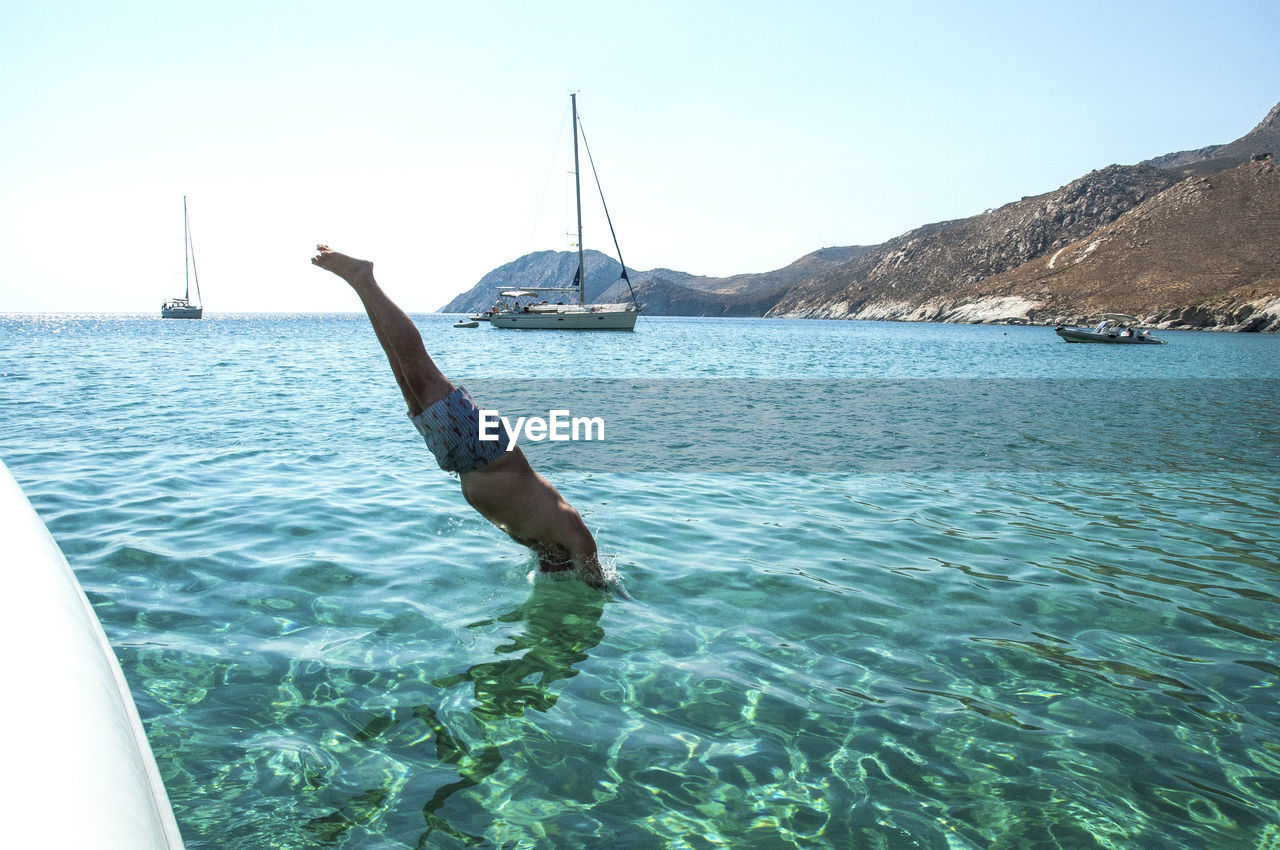 Shirtless man diving in sea against clear sky