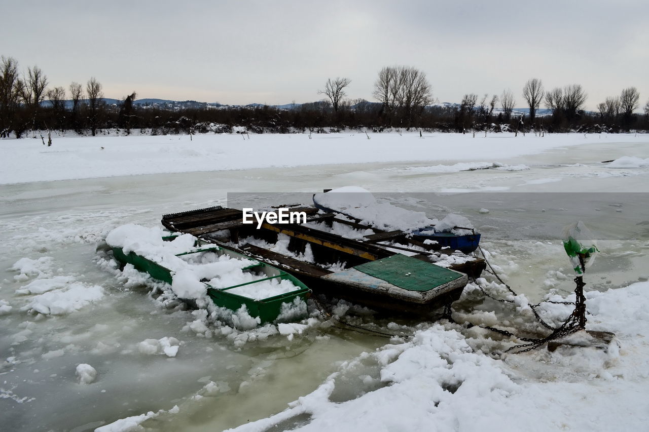 Boats on the frozen river covered with snow and ice