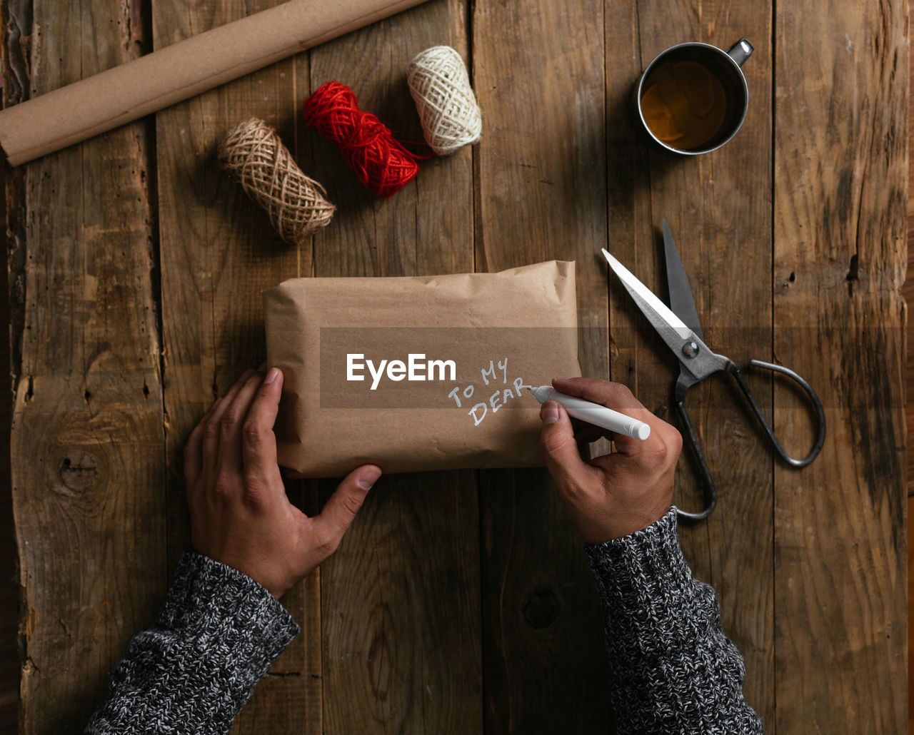 Top view of a man's hands packing a gift on a wooden table