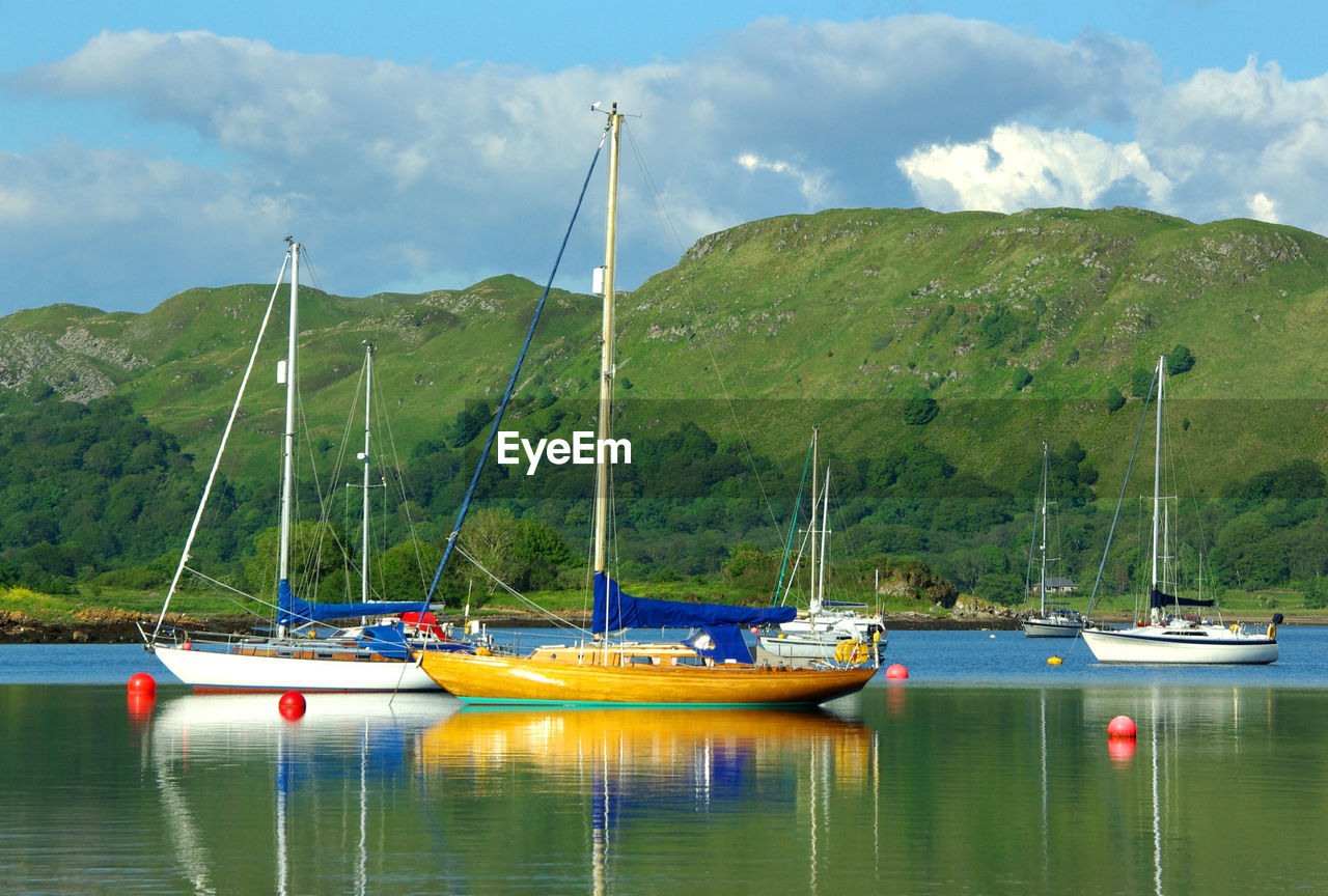 BOATS MOORED ON LAKE AGAINST SKY