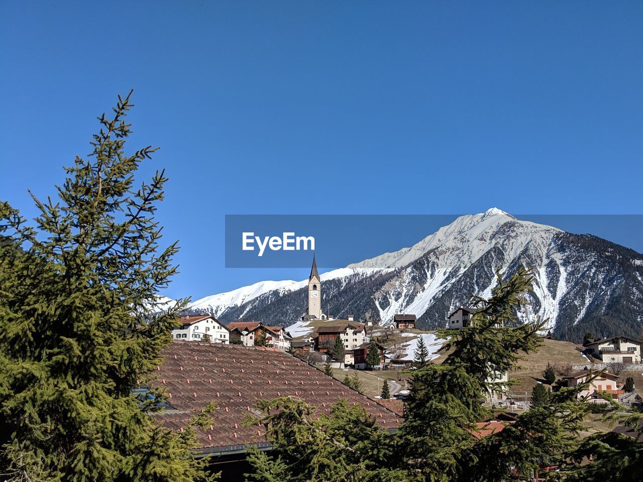Village in front of snowcapped mountain against clear blue sky