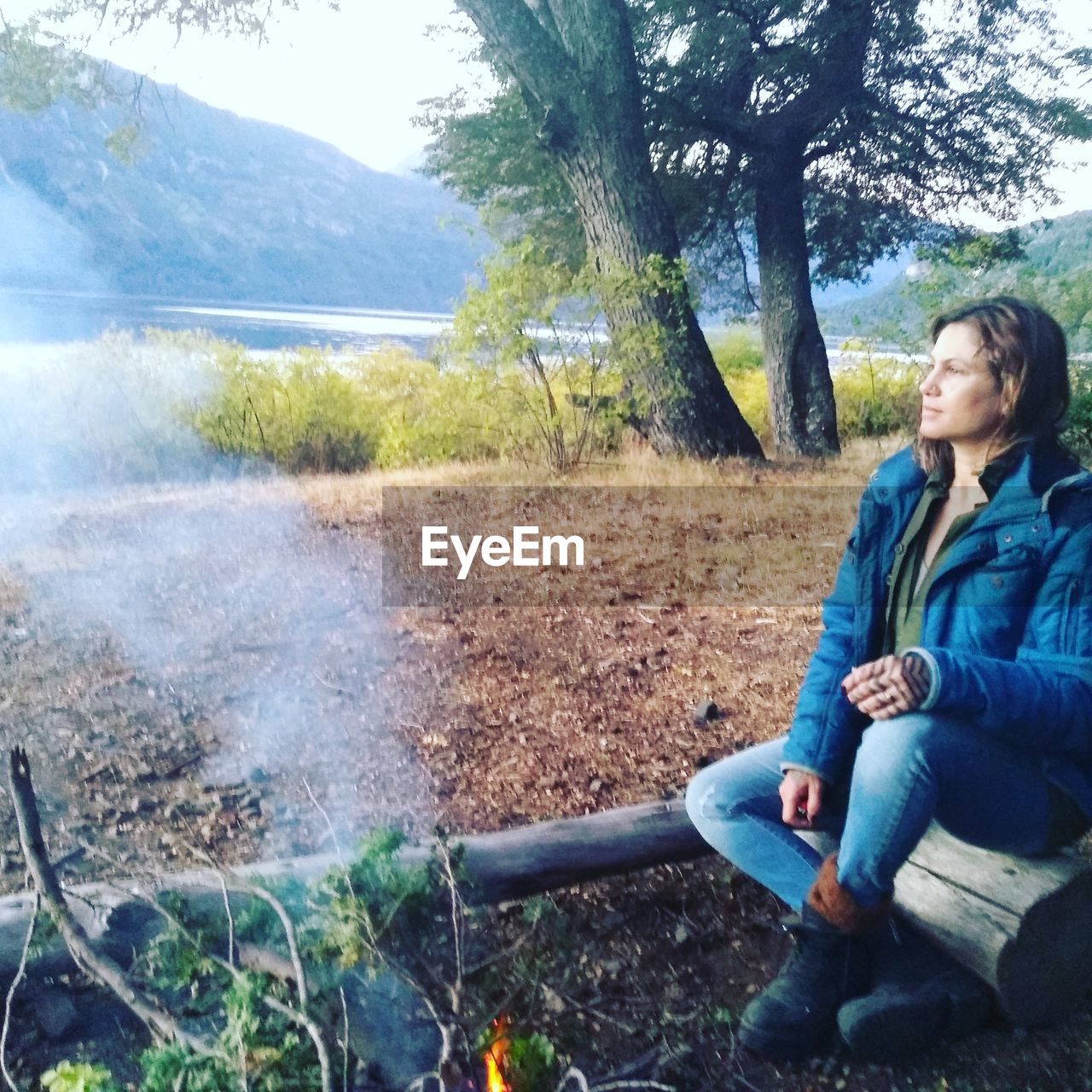 Thoughtful woman sitting on log in forest