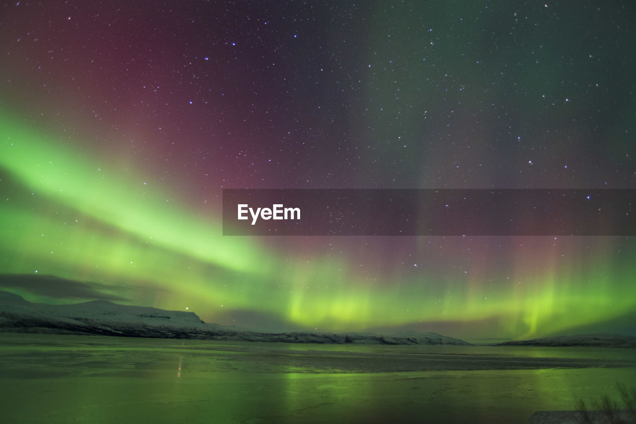 Scenic view of sea and aurora against sky at night