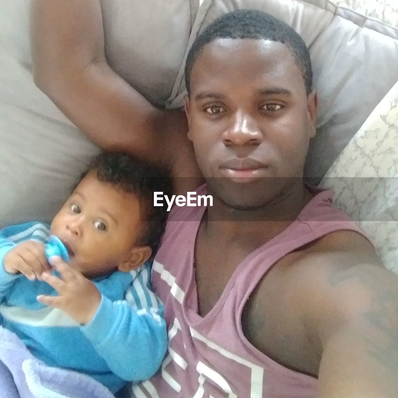 HIGH ANGLE PORTRAIT OF FATHER AND SON BABY ON BED