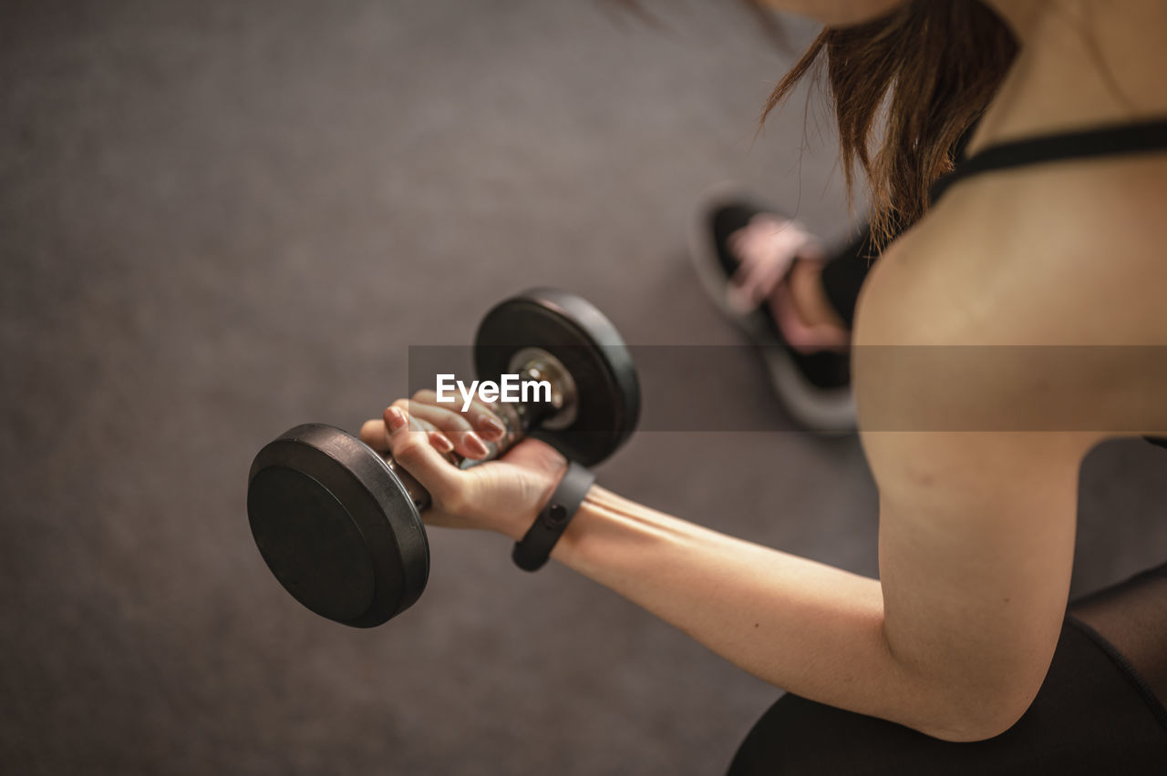High angle view of young woman lifting dumbbell in gym
