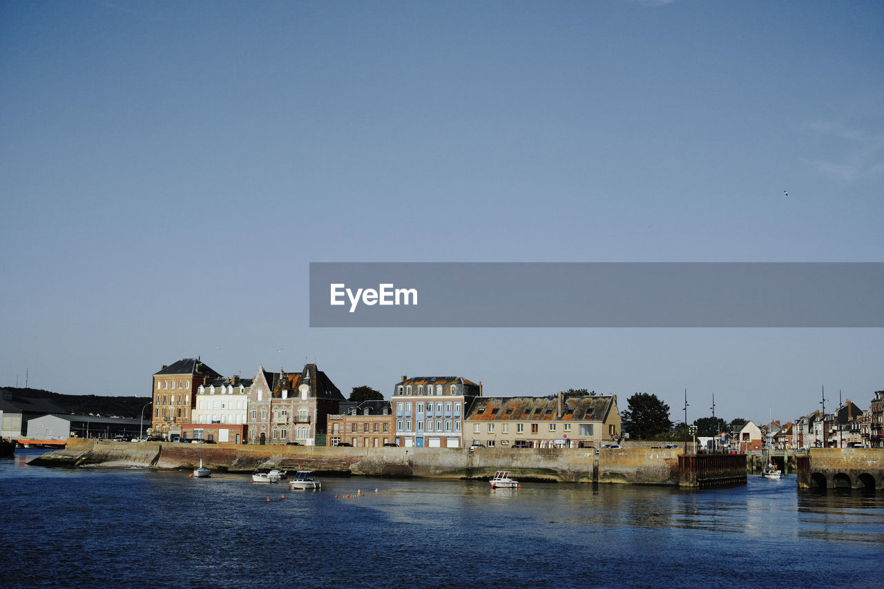 RIVER AMIDST BUILDINGS AGAINST CLEAR SKY