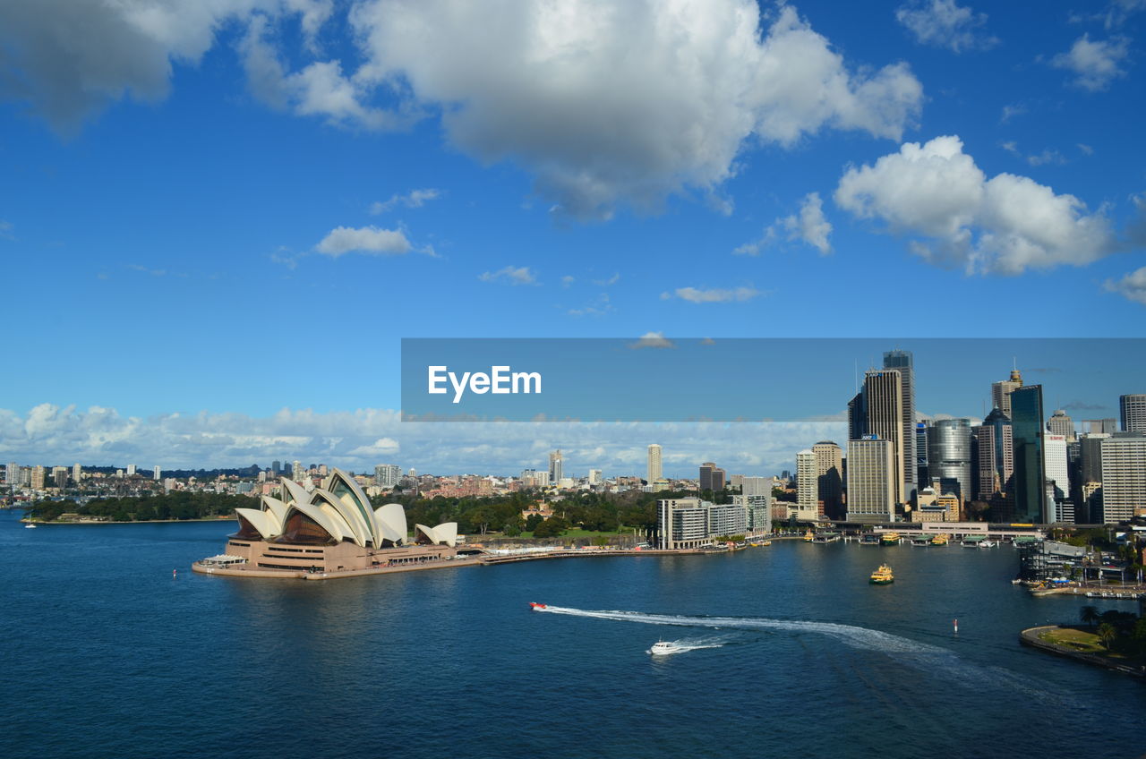 City at waterfront against cloudy sky