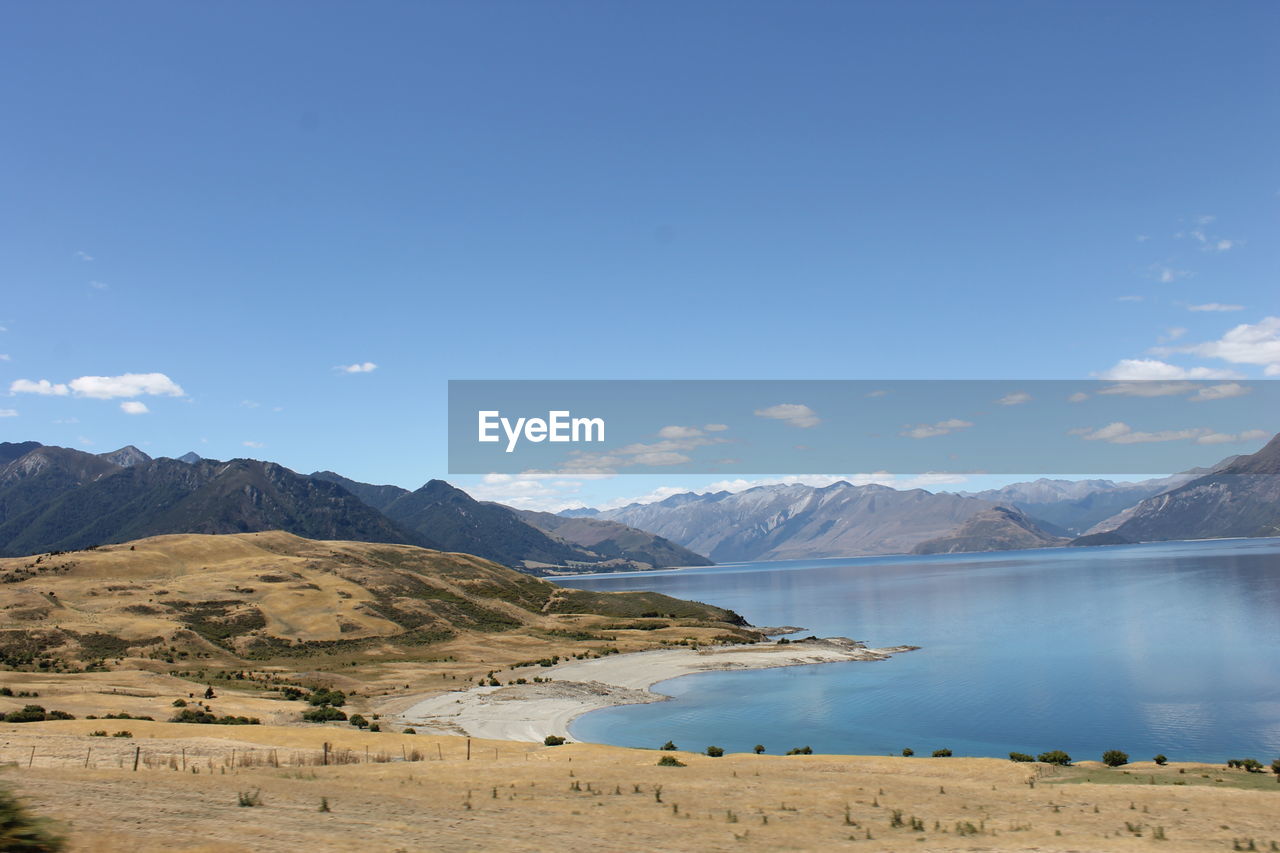 Scenic view of lake and mountains against blue sky