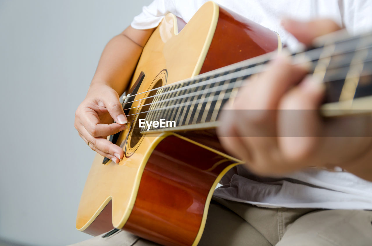 Midsection of woman playing guitar