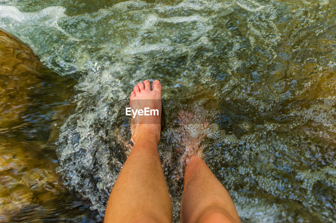 Low section of woman feet in water