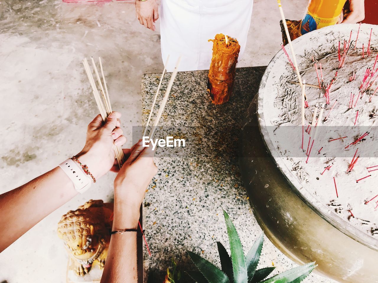 Cropped hands of woman holding incense sticks at temple