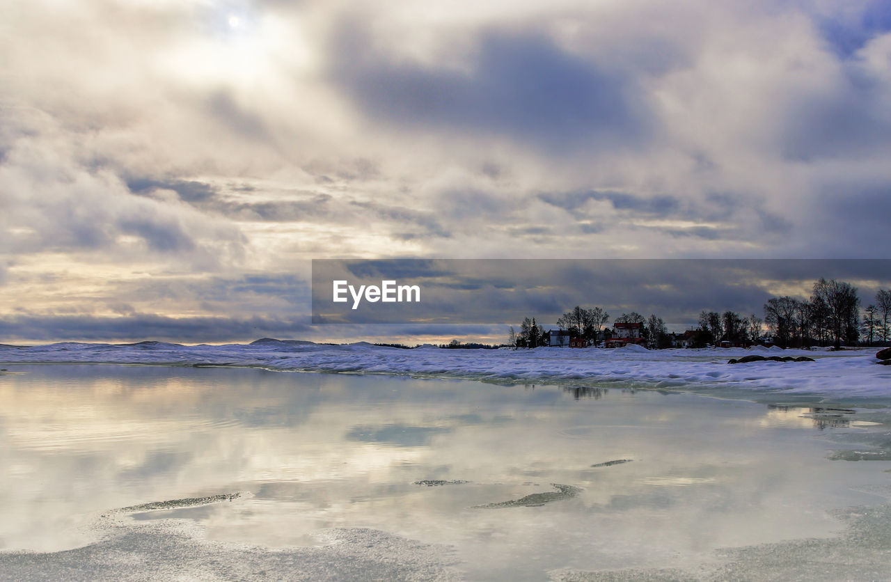 SCENIC VIEW OF FROZEN LAKE AGAINST SKY