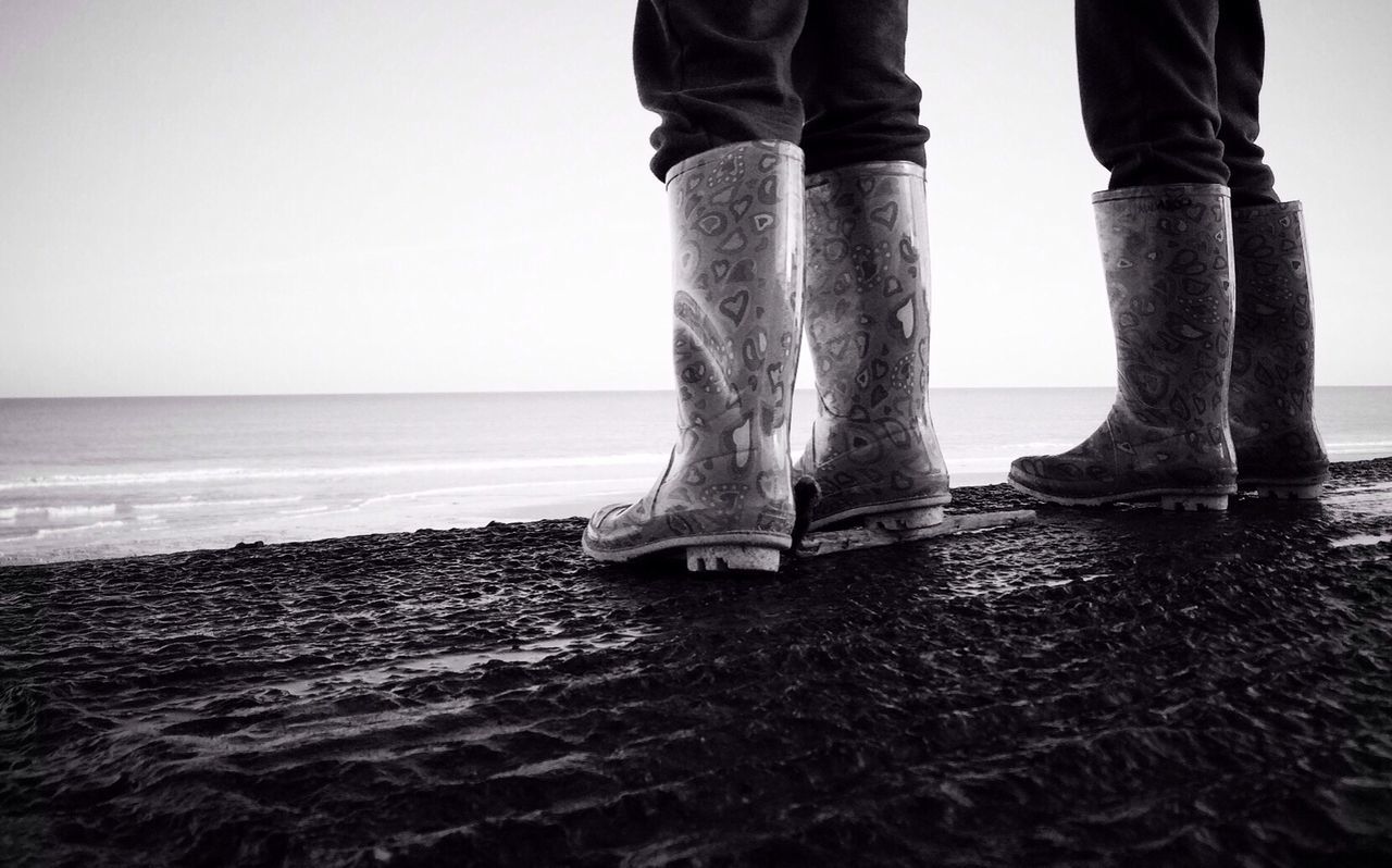 Low section of couple in wellington boots at beach