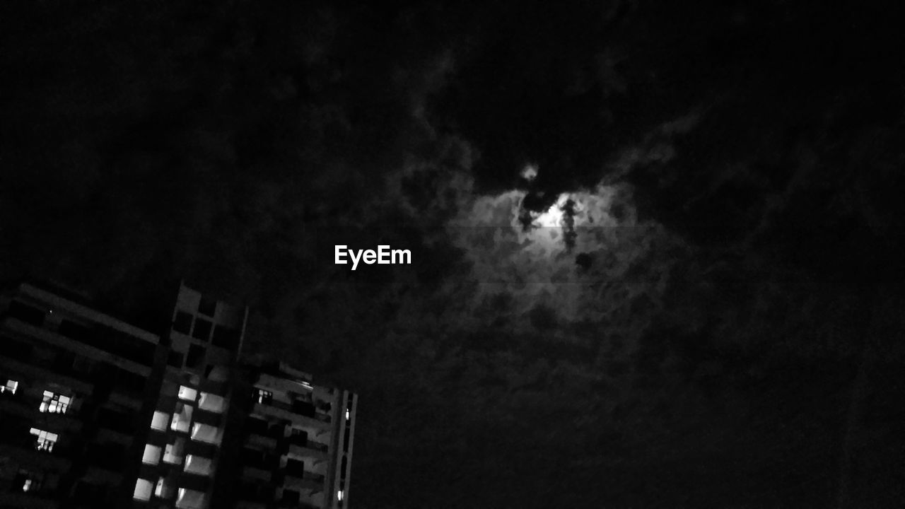 LOW ANGLE VIEW OF ILLUMINATED BUILDINGS AGAINST SKY AT NIGHT