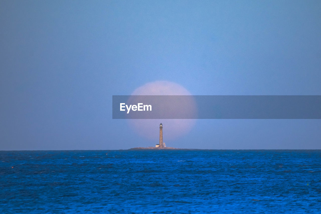 Full moon rising behind the boon island lighthouse