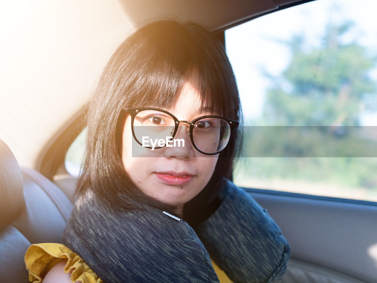 Portrait of young woman wearing eyeglasses sitting in car