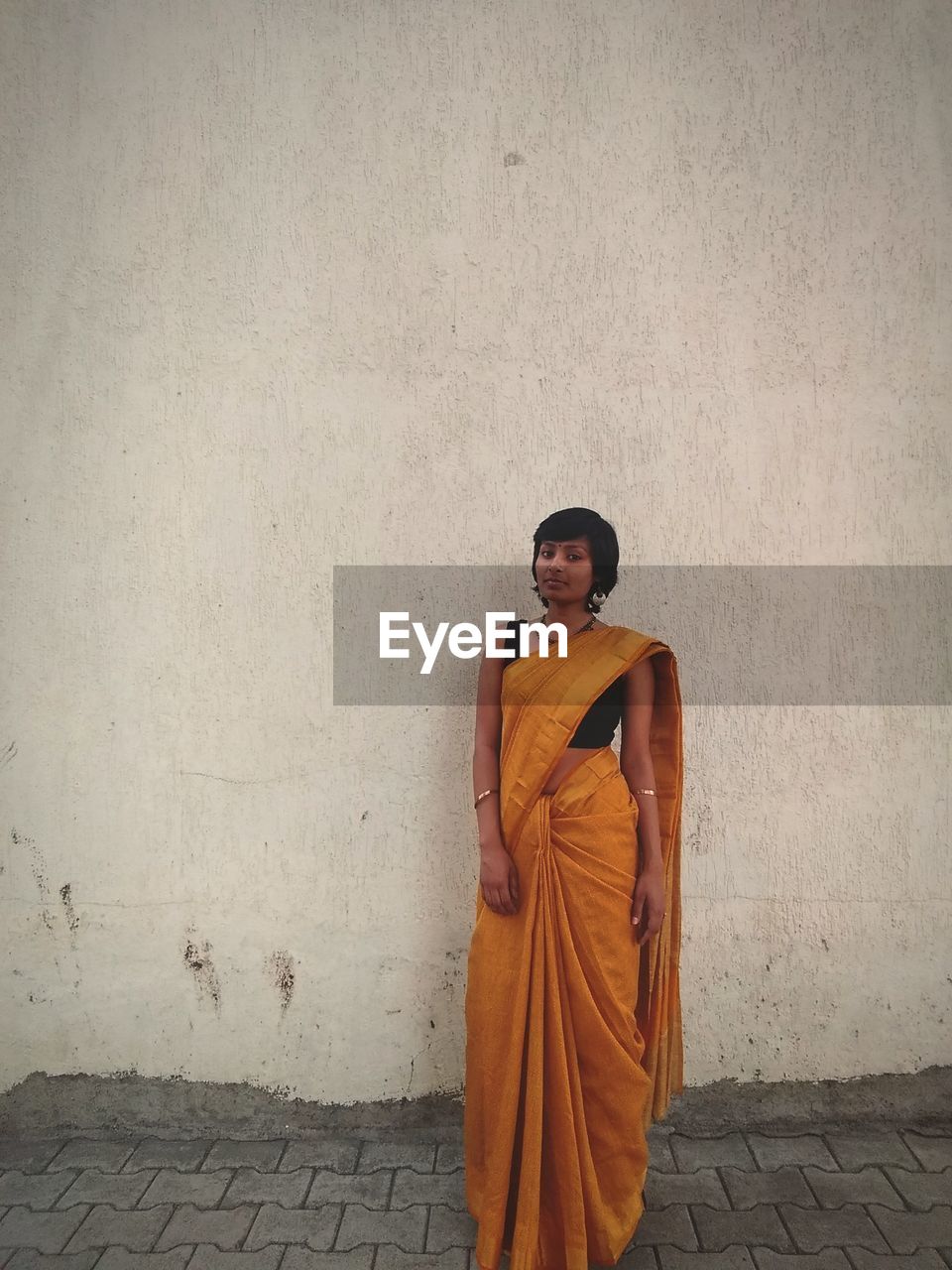 Portrait of woman standing against wall