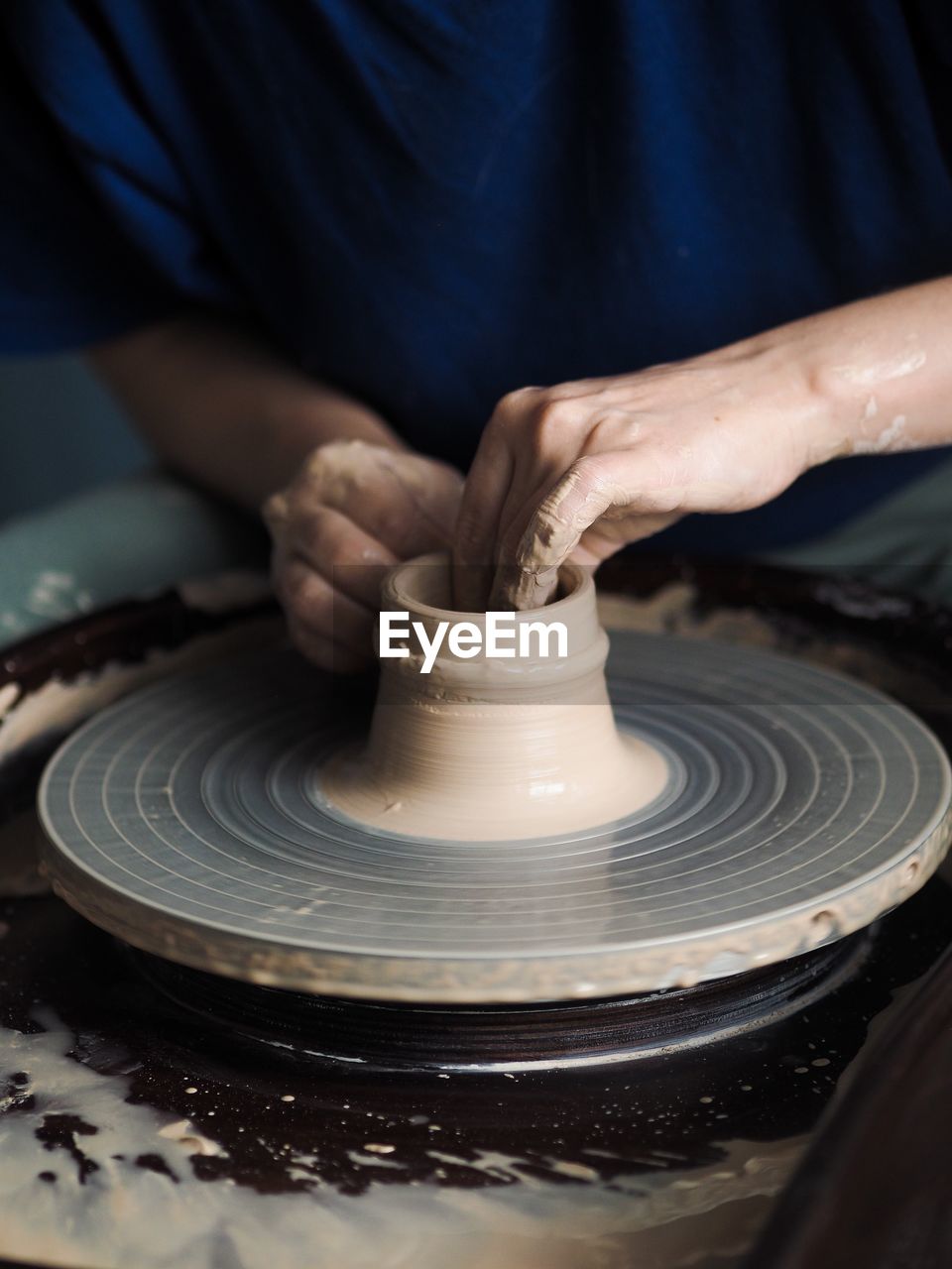 Woman starts to create a ceramic cup on the pottery wheel. working with clay on potter's wheel.