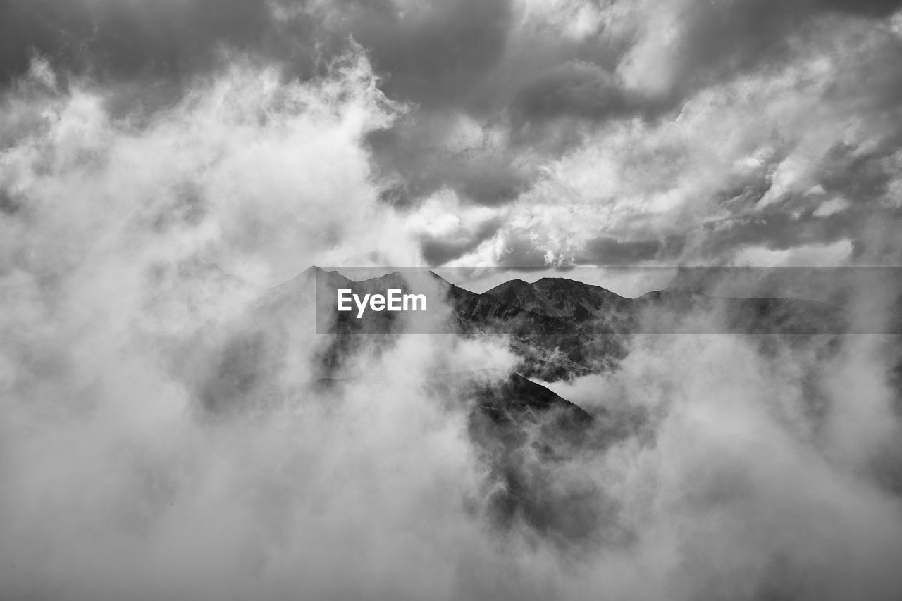 Scenic view of clouds covering mountains against sky