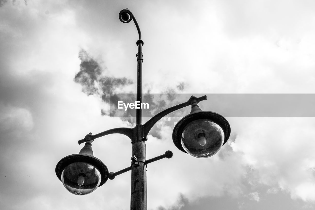 Low angle view of street light and cctv camera against sky