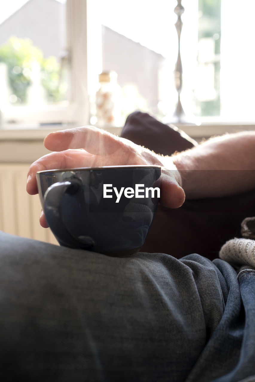 MIDSECTION OF MAN HOLDING COFFEE CUP
