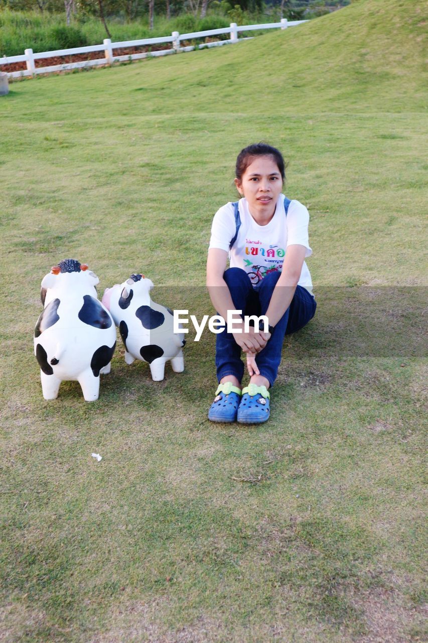 High angle portrait of woman sitting on field by toy animal