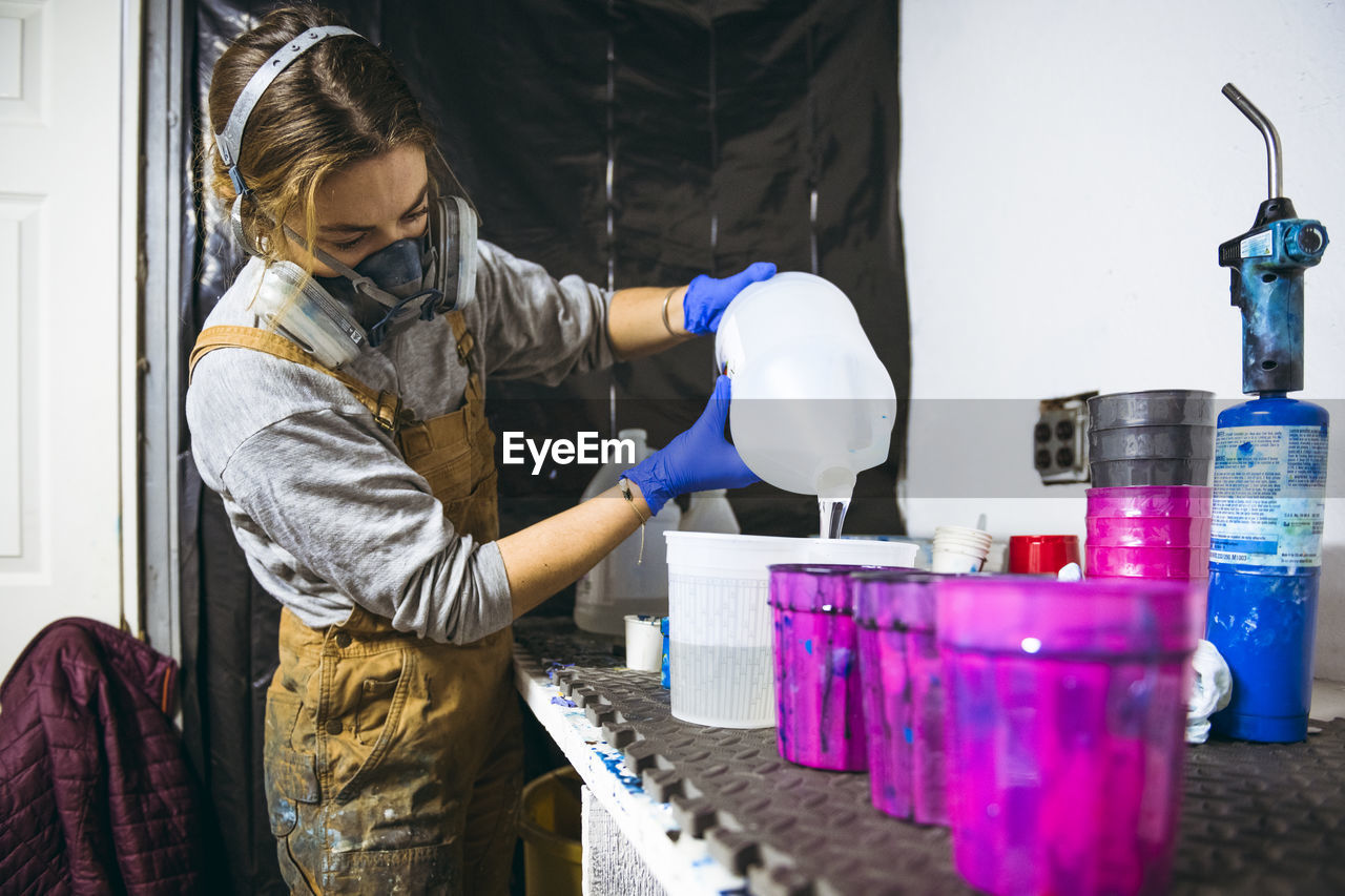 Female resin artist mixing and pouring with respirator mask