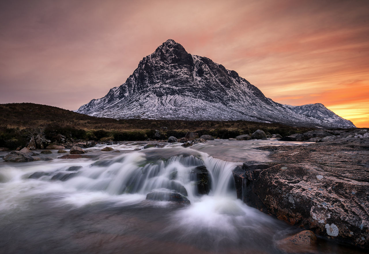 Scenic view of waterfall against sky during sunset