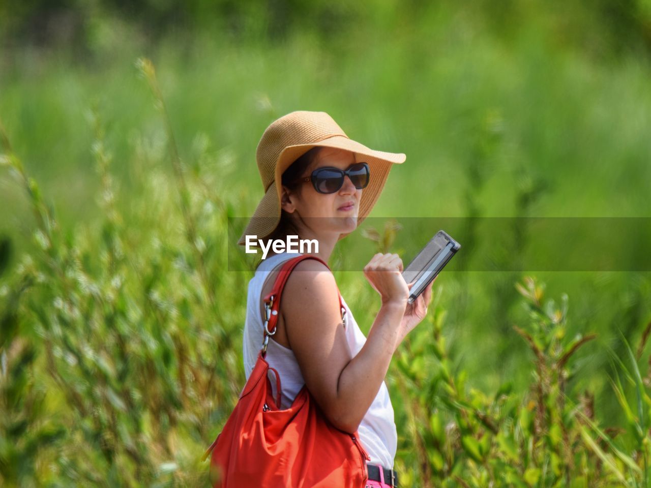 Woman using digital tablet while standing on field 