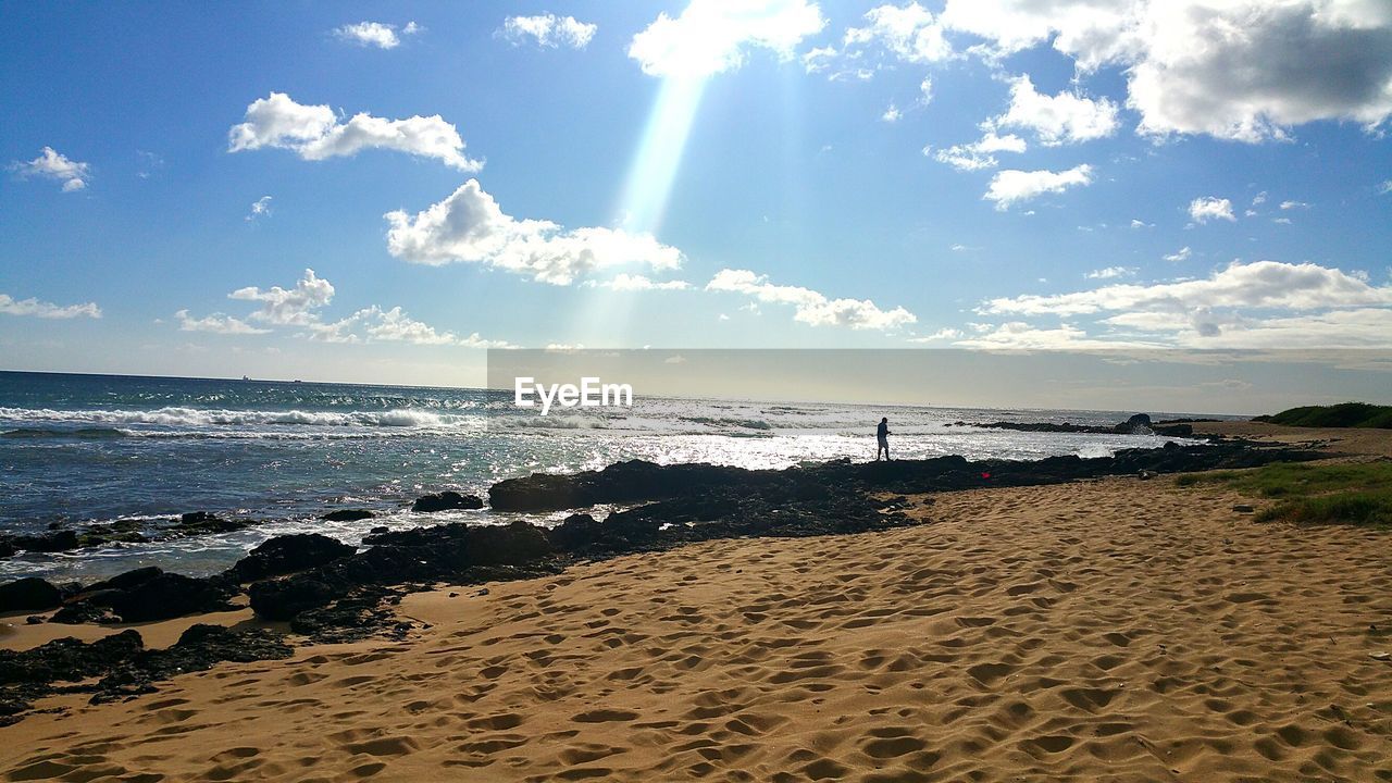 Scenic view of silhouette person walking on shore at beach against sky