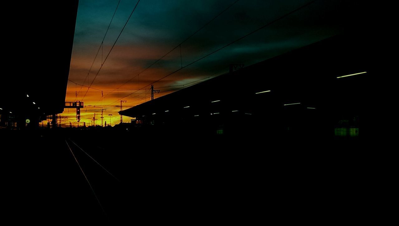 Silhouette railroad station against sky during sunset