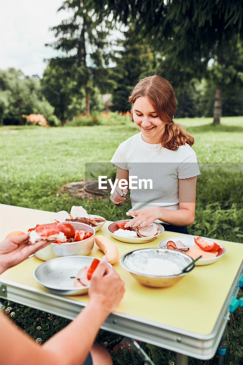 Family having breakfast outdoors on camping during summer vacation