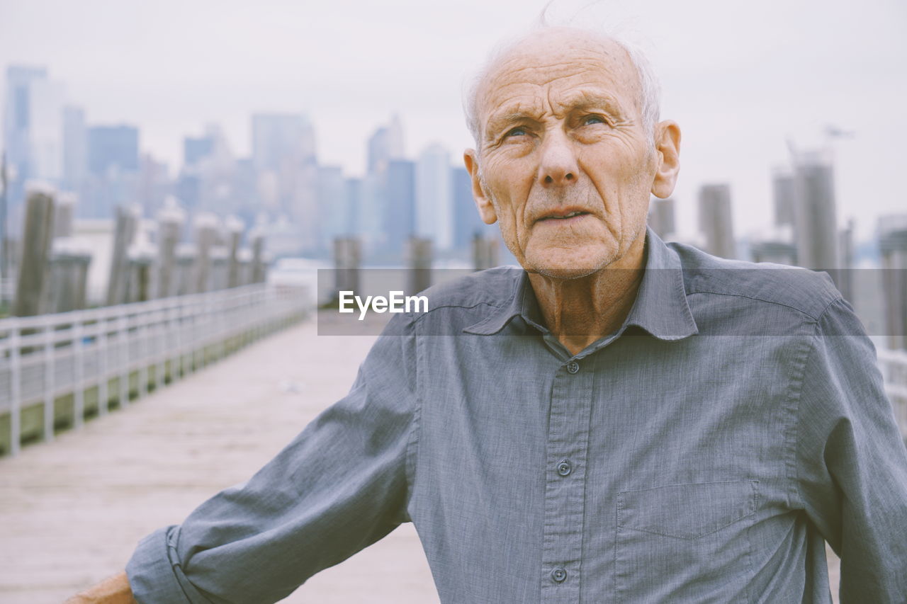 Senior man looking away while standing in city