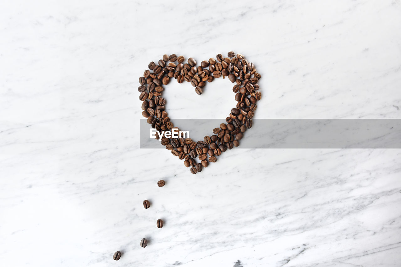 High angle view of coffee beans arranged in heart shape on marble table