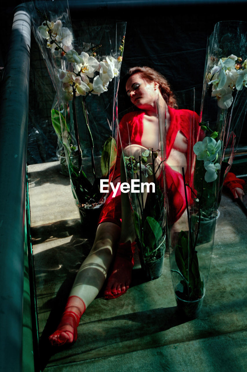 PORTRAIT OF WOMAN SITTING WITH FLOWERS IN GLASS