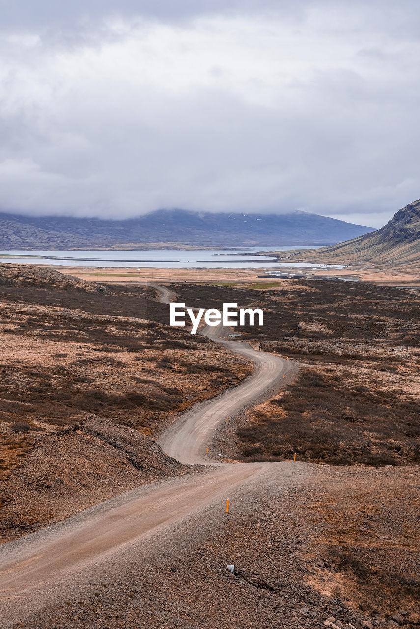 Scenic view of empty road amidst landscape at eastfjords against cloudy sky