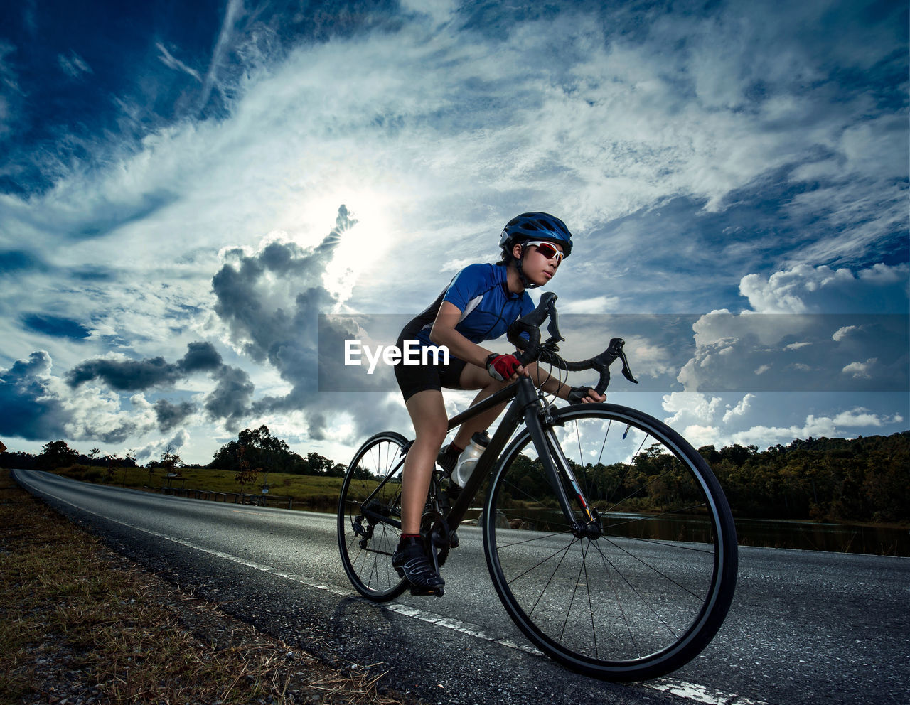 Teenage girl riding bicycle on road against sky