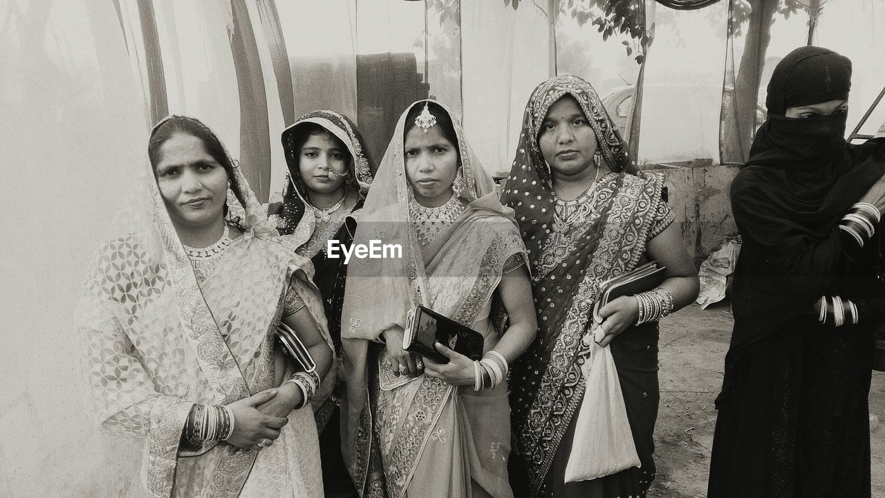 Women in traditional clothing standing on footpath