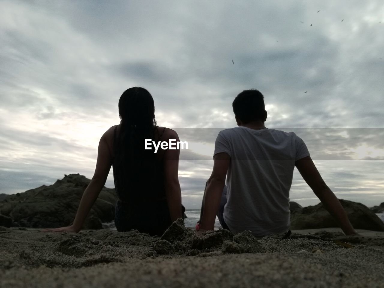 REAR VIEW OF TWO MEN ON LANDSCAPE AGAINST SKY