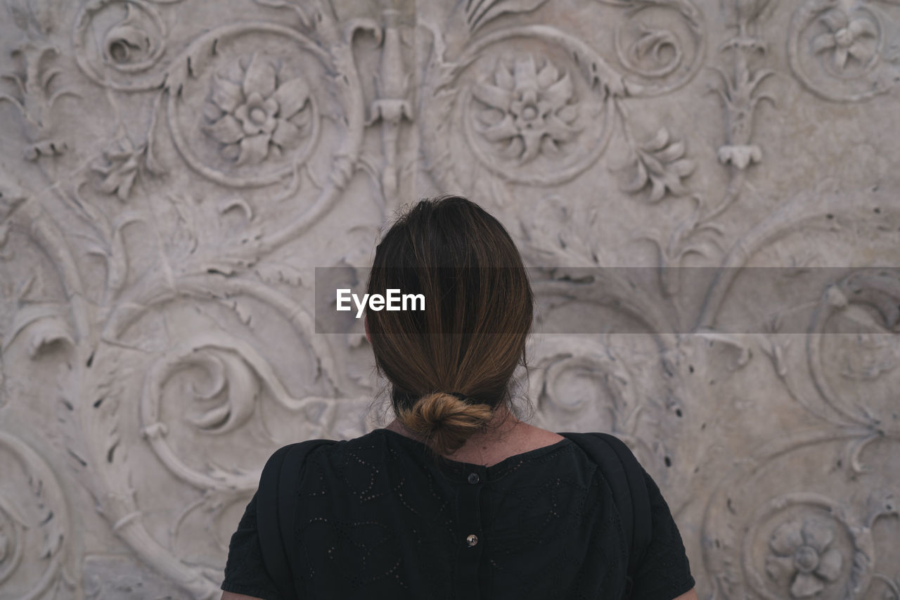 Rear view of woman standing against wall