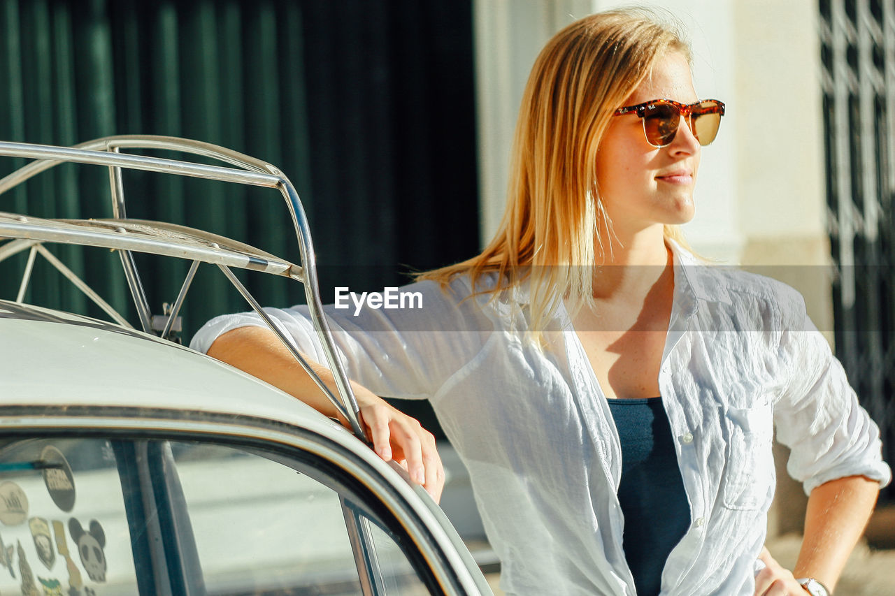 adult, women, one person, fashion, sunglasses, glasses, young adult, transportation, mode of transportation, lifestyles, blond hair, casual clothing, car, smiling, spring, architecture, motor vehicle, city, vision care, happiness, female, vehicle, clothing, eyewear, travel, emotion, relaxation, outdoors, person, hairstyle, looking, city life, portrait, day, summer, leisure activity, cheerful, sunlight