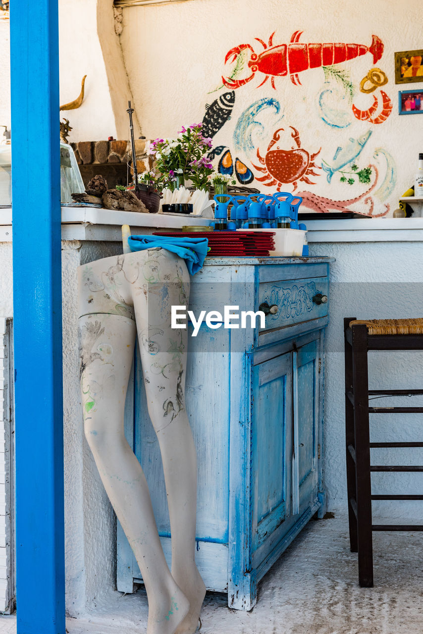 LOW SECTION OF WOMAN WITH POTTED PLANTS AGAINST WALL