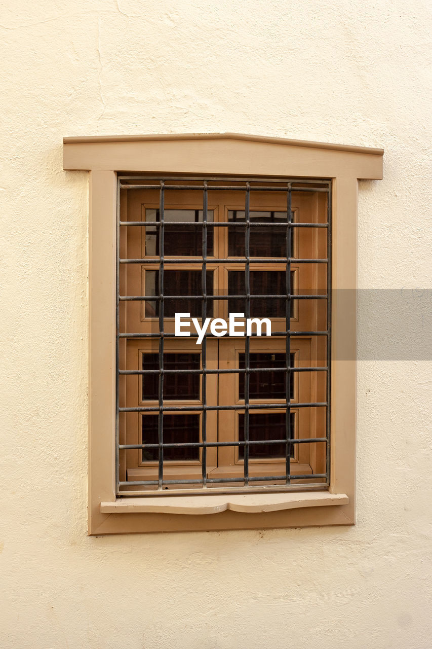 Window in wall with bars. frame with glass behind bars.